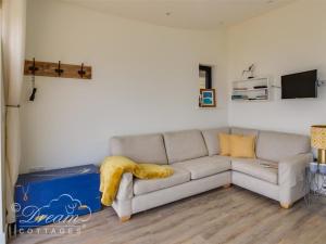 sala de estar con sofá y manta amarilla en The Wave, en West Bay
