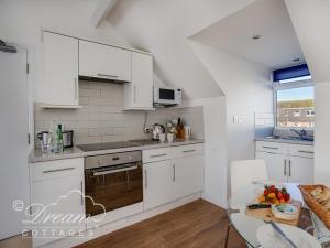 een keuken met witte kasten en een tafel bij Dream View in Weymouth +16 foto's
