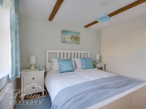 a bedroom with a white bed with blue pillows at Ammonite Cottage in Portland
