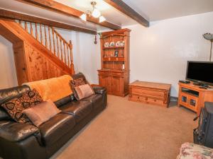 een woonkamer met een leren bank en een televisie bij Shires Rest in Buxton