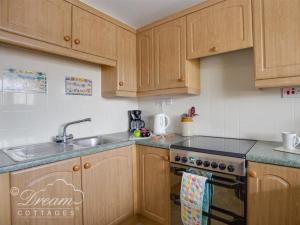 a kitchen with wooden cabinets and a stove top oven at Jurassic View in West Bay +9 photos