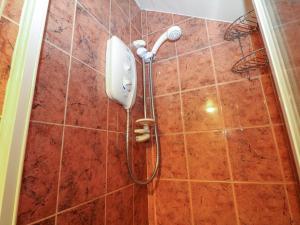 a shower with a phone on a tiled wall at Shires Rest in Buxton