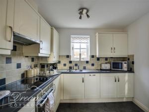 eine weiße Küche mit weißen Schränken und einem Fenster in der Unterkunft Rupert Cottage in Weymouth + 19 Fotos