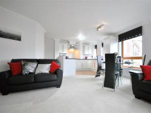 a living room with a black couch and a kitchen at Old Harbour View in Weymouth