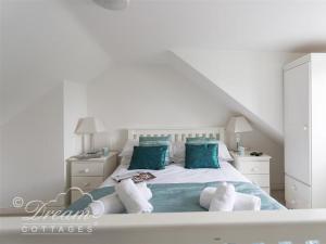 ein weißes Schlafzimmer mit einem Bett mit blauen Kissen in der Unterkunft Ocean Swell in Weymouth