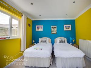 2 Betten in einem Zimmer mit blauen und gelben Wänden in der Unterkunft Bowleaze View in Weymouth