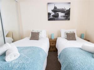 two beds sitting next to each other in a room at Buccaneer Cottage in Weymouth