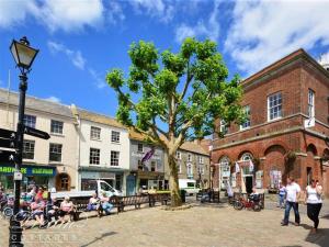 a group of people sitting on benches next to a tree at Grazeland Cottage in Bridport