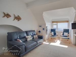 a living room with a blue couch and two chairs at Dream View in Weymouth