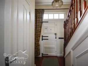 einen Flur mit einer Treppe mit Tür und Fenster in der Unterkunft Rupert Cottage in Weymouth