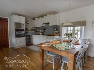 a kitchen with a wooden table and white cabinets at The Old Reading Room in Portesham