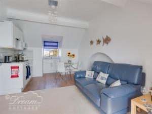 a living room with a blue couch and a kitchen at Dream View in Weymouth