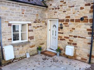 ein Backsteingebäude mit einer weißen Tür und zwei Fenstern in der Unterkunft Manor Farm House Cottage in Kettering