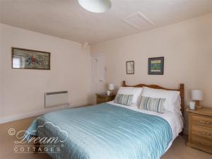 a bedroom with a large bed with a blue blanket at Tavern Way in Corfe Castle