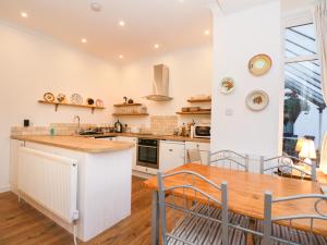a kitchen with white cabinets and a wooden table at 2 Kilmun Court in Dunoon