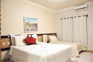 a bedroom with two beds with white and red pillows at Fazenda Hotel Pedra dos Ventos in Quixadá