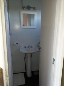 uma casa de banho branca com um lavatório e um espelho em El Vagón em Sierra de la Ventana