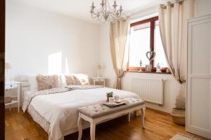 a white bedroom with a bed and a table at Apartmán NINA in Veľká Lomnica
