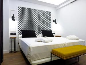 a bedroom with two beds and a yellow bench at Hotel Colón Plaza in Valladolid