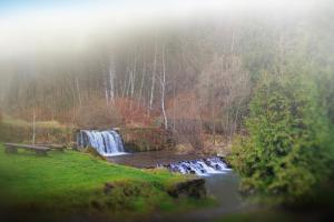 a waterfall in a park with a bench next to a river at Pod Wodospadem in Szczyrk