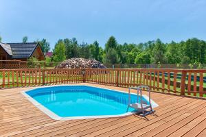 a swimming pool on a deck with a wooden fence at Rezydencja Limajno in Dobre Miasto