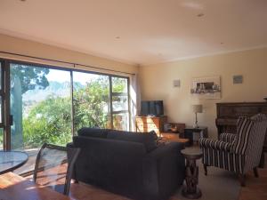a living room with a black couch and a window at Swallow's Nest in Somerset West