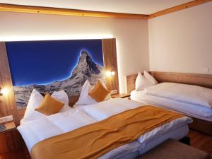 two beds in a room with a picture of a mountain at Typically Swiss Hotel Täscherhof in Täsch