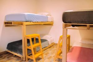a room with three bunk beds and two stools at Bababuy Hostel in Bogotá