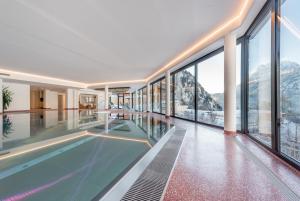 een groot zwembad in een gebouw met ramen bij Hotel Burgstein - alpin & lifestyle in Längenfeld