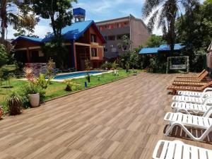 a deck with white chairs and a pool at Hotel Amayal in Puerto Iguazú