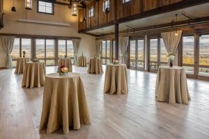 un groupe de tables avec des fleurs dans une pièce avec des fenêtres dans l'établissement Sage Lodge, à Pray