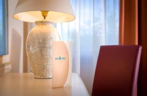 una lámpara sentada en una mesa junto a un jarrón en Hotel Des Alpes, en Rosta