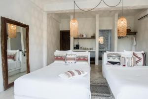 two beds in a room with white walls and chandeliers at Icaco Island Village - Adults Only in Isla Mujeres +115 photos