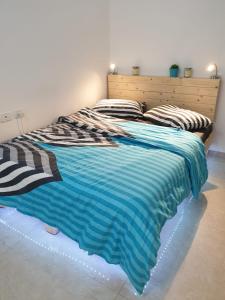 a bed with a blue and white blanket on it at סויטה בלב המדבר. in Beʼer Ora