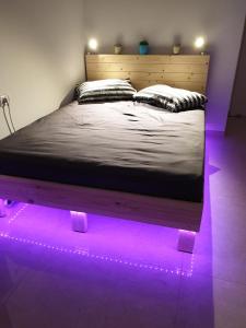 sypialnia z łóżkiem z fioletowymi lampkami w obiekcie סויטה בלב המדבר. w mieście Beʼer Ora