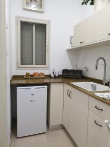 a white kitchen with a sink and a dishwasher at סויטה בלב המדבר. in Beʼer Ora