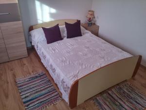 a bedroom with a bed with purple pillows on it at Holiday Home Ruža in Mirce
