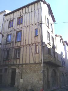 - un vieux bâtiment en pierre avec un balcon sur le côté dans l'établissement La Perle du Rouergue, à Villefranche-de-Rouergue