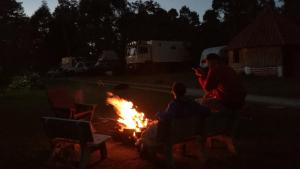 a group of people sitting around a fire at night at Al Bosque Hostel & Glamping in Santa Elena
