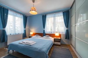 a blue bedroom with a bed and blue curtains at Apartamenty Tyrol in Szczawnica