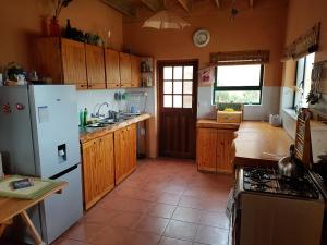 Una cocina con gabinetes de madera y un refrigerador blanco. en Pelagonia, en Bettyʼs Bay