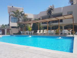 a swimming pool with chairs and a pavilion at Belle Sand Hotel in Ica