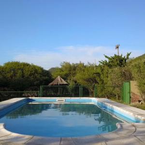 a swimming pool with blue water in a yard at Cabañas El Aguaribay in Capilla del Monte
