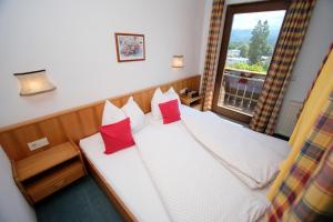 Un dormitorio con una cama con almohadas rojas y una ventana en Ferienwohnungen Fiala-Köfer en Pörtschach am Wörthersee