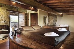 sypialnia z dużym łóżkiem i kamienną ścianą w obiekcie Borgo Casa al Vento w mieście Gaiole in Chianti