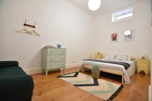 a bedroom with a bed and a dresser and a couch at Casa Pé da Cabra in Coimbra