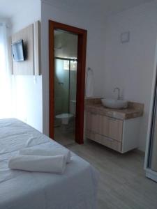 een witte slaapkamer met een wastafel en een badkamer bij Casa condominio fechado Arraial D’ajuda in Arraial d'Ajuda