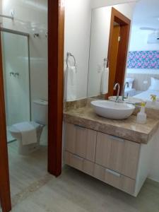 een badkamer met een wastafel, een toilet en een spiegel bij Casa condominio fechado Arraial D’ajuda in Arraial d'Ajuda