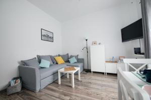 een woonkamer met een grijze bank en een tafel bij Apartament PRZEDZAMCZE in Toruń