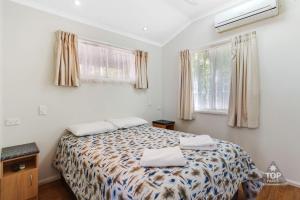 a bedroom with a bed and two windows at Charters Towers Tourist Park in Charters Towers
